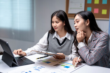 Two businesswomen planning strategy using digital tablet and documents at office desk
