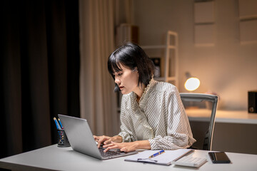 Young asian manager working late on laptop in home office