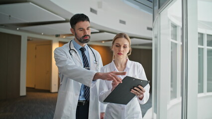 Fototapeta premium Doctors reviewing patient chart in hospital closeup. Medical team walking hall