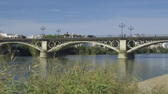 personas y coches pasando por encima del puente de Triana que divide las dos orillas por encima del rio guadalquivir
