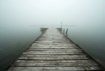Fototapeta premium Weathered Wooden Pier Leading to a Misty Horizon