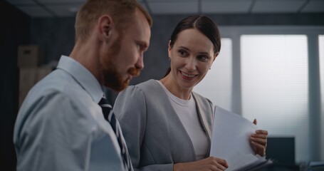 Fototapeta premium Two office employees working in modern international company: Successful marketing professionals or financial workers analyze documents and projects, discuss investments, brainstorm business strategy.