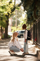 Side view. Schoolgirl with her mother are outdoors together