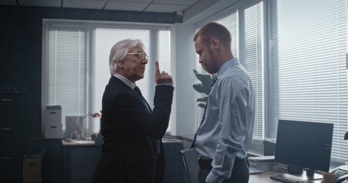 In modern office of bank: Irritated and angry boss having fight with male company employee over unsuccessful business deal. Senior team leader with papers loses temper and yells at man. Slow Motion.