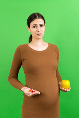 apple and a heap of pills in pregnant woman's hands at colorful background with copy space. Making...