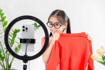 social media market concept. Asian cute girl seller showing clothes during live streaming in the mobile application.