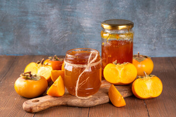Persimmon jam. Sweet autumn homemade jam or marmalade canning preserves in a jar, with whole and...