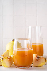 Fresh homemade apple quince juice in portioned glasses, with whole and sliced quinces c in the background
