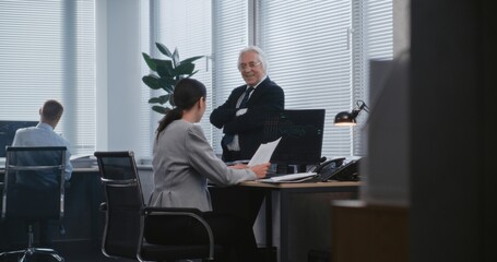 Two different business analysts, adult woman and senior man, discuss development of investment project, potential financial results. Planning business strategy. Work in modern financial corporation.
