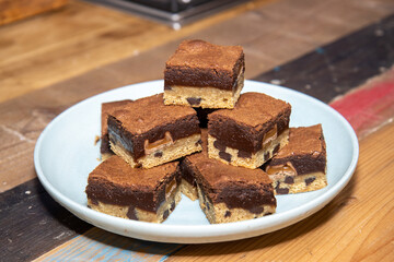 A plate of delicious chocolate brownies on a wooden kitchen work top showing the tasty deserts in a pile ready to be eaten