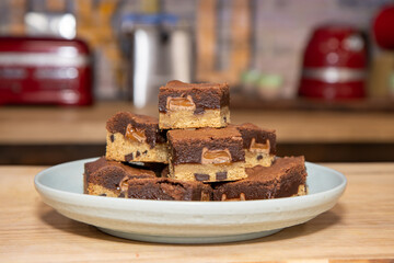 A plate of delicious chocolate brownies on a wooden kitchen work top with kitchen appliances in the...