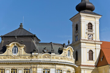 A baroque-style church tower in Sibiu, Romania, featuring an onion-shaped dome, a clock face, and arched windows.
