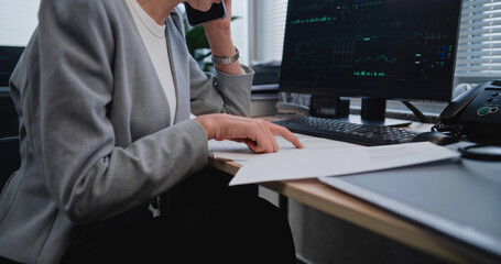 Close up of female financier working with paper documents and financial metrics, communicating with...