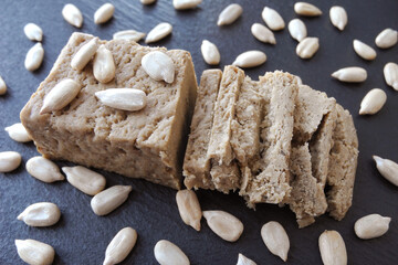 Pieces of halva with sunflower seeds on black slate board
