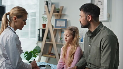 Professional doctor discussing diagnosis with with father daughter in clinic.