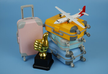 Airplane model, gold thumbs up cup and many suitcases on blue background.