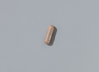 Brown Medical capsule on grey top view, hard shadows. Taking dietary supplements