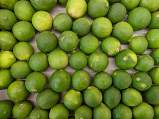 A close-up of vibrant green key limes, clustered together in a fresh, zesty display.