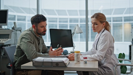 Clinic doctor advising medication after health checkup. Patient checking pills