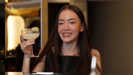 Smiling beautiful woman zipping Margarita cocktail savoring tasty drink making special time by bartender at luxurious bar creating moment meeting with friends or a couple vibrant nightclub. Vinosity.