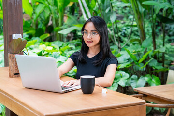 Young Woman Working on Laptop in Lush Greenery