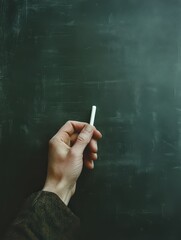 Fototapeta premium teacher holds a small piece of white chalk, writing neatly on a green chalkboard, depicting a classic scene of instruction in a traditional classroom.