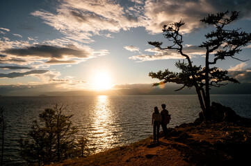 A Chinese couple in love looks at the sunset on the shore of Lake Baikal