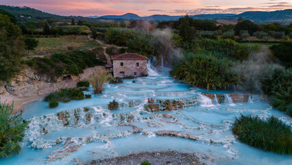 Relaxing in the serene thermal waters of Saturnia, Tuscany, at sunset surrounded by lush nature