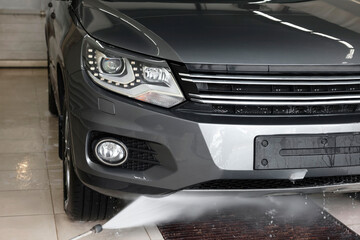 Washing auto with high pressure water jet at car wash, closeup