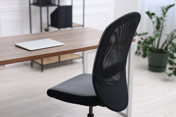 Black chair, laptop and desk in office