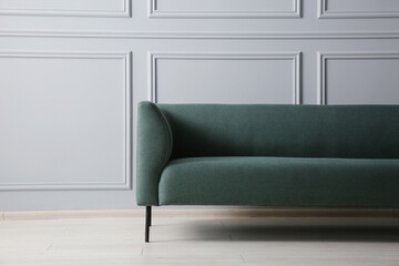 One stylish sofa near grey wall indoors