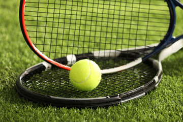 Tennis rackets and ball on green artificial grass, closeup