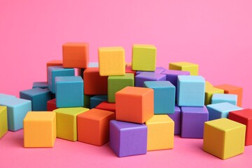 Many wooden colorful cubes on pink background