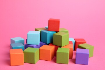 Many wooden colorful cubes on pink background