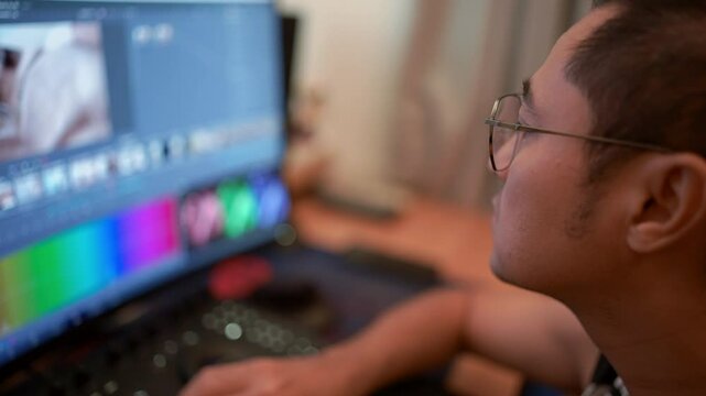 In the video editing room Asian man working using the Grading Color panel on his video creation project.