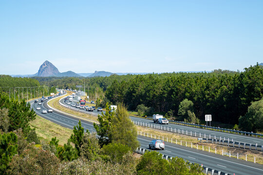 Vehicles driving the M1 Bruce Highway with glass house mountains in background.