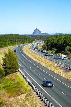 Vehicles driving the M1 Bruce Highway with glass house mountains in background.