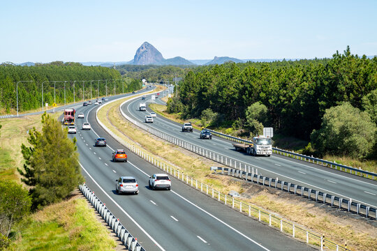 Vehicles driving the M1 Bruce Highway with glass house mountains in background.