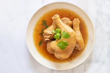 A delicious plate of cooked chicken drumsticks served in a savory broth with fresh herbs, perfect for a comforting meal.