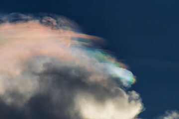 A stunning cloud formation with iridescent colors against a deep blue sky, creating a serene and...