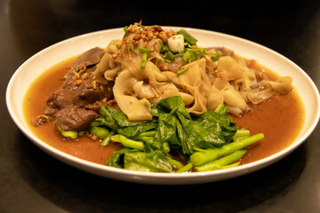 Stewed duck intestine in brown soy soup on plate dipping with spicy chili sauce.