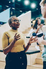 Young african american woman explaining information to male colleague standing on break in...
