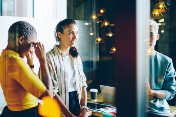 Serious male and female colleagues talking to each other discussing plannings for project together, working process through glass of clever multiracial employees  brainstorming and communicating