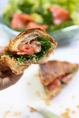 A delicious croissant filled with smoked salmon and fresh greens, perfect for a gourmet breakfast or brunch.