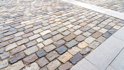 A gray and white cobblestone sidewalk with a gray and white border. The cobblestone is laid out in a pattern and the border is made of gray and white stones