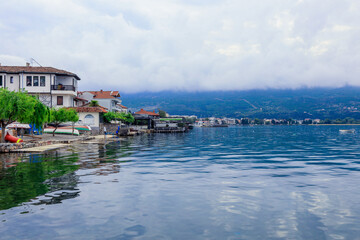 Obraz premium Tranquil waters of Lake Ohrid reflect cloudy skies in Ohrid Macedonia during a serene afternoon stroll by the lakeside