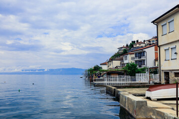 Obraz premium Serene lakeside view of Ohrid Macedonia with charming houses and calm waters on a cloudy day