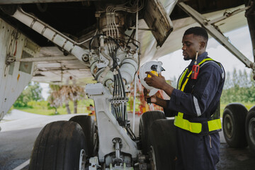 Mechanics inspect the engines of a large plane before takeoff at a summer airport..