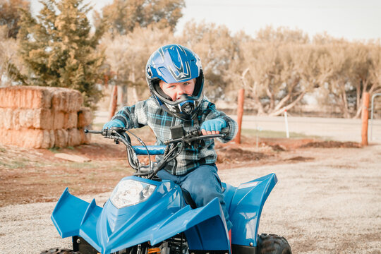 Little boy riding quad bike on farm