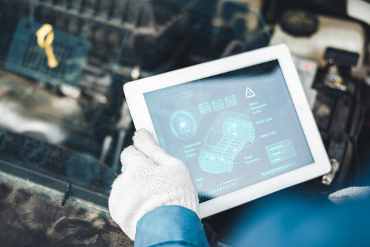 A gloved mechanic uses a digital tablet to diagnose a vehicle's system, displaying data about battery and engine components. - Powered by Adobe